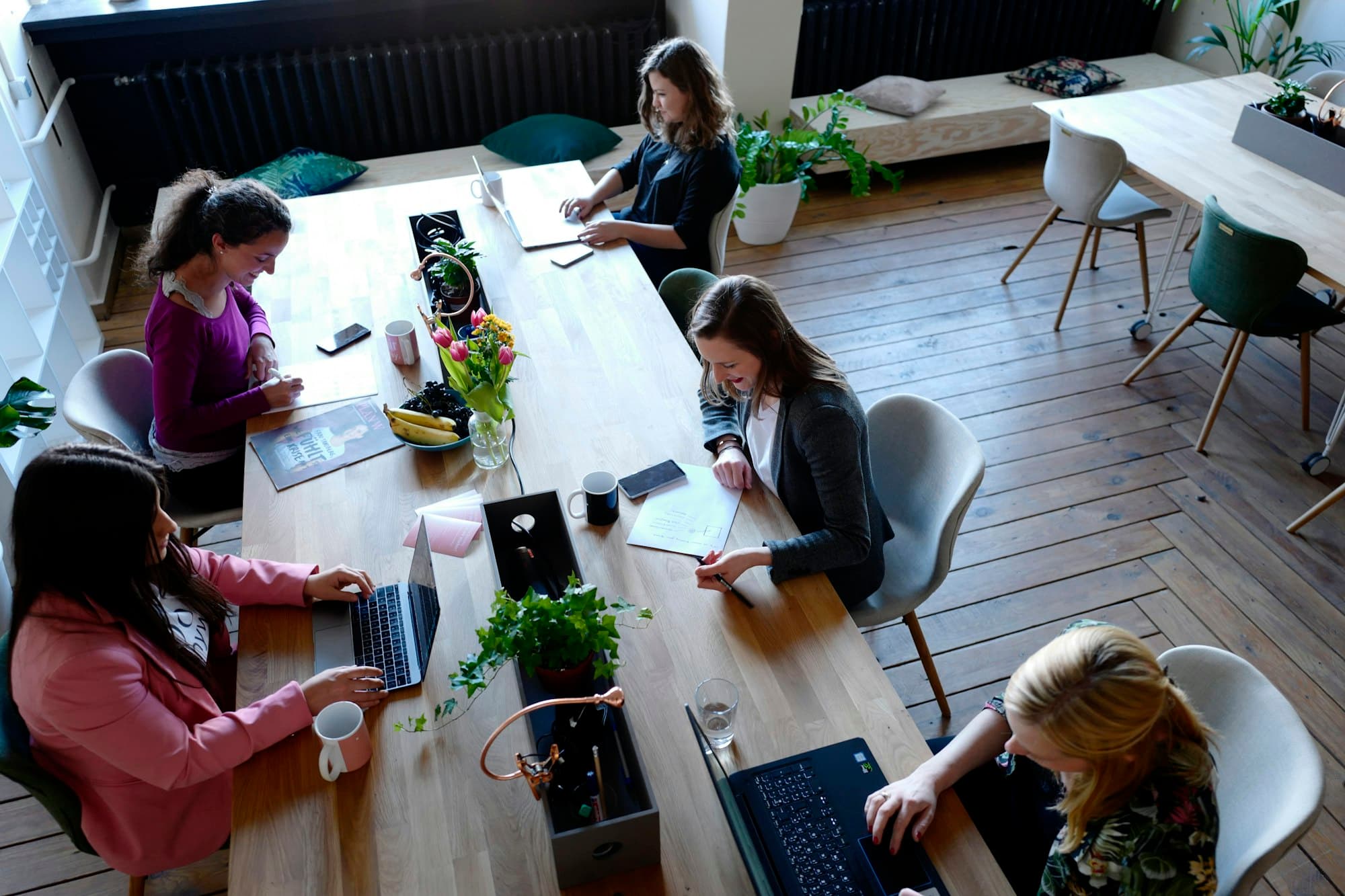 A small team working on laptops around a long wooden table