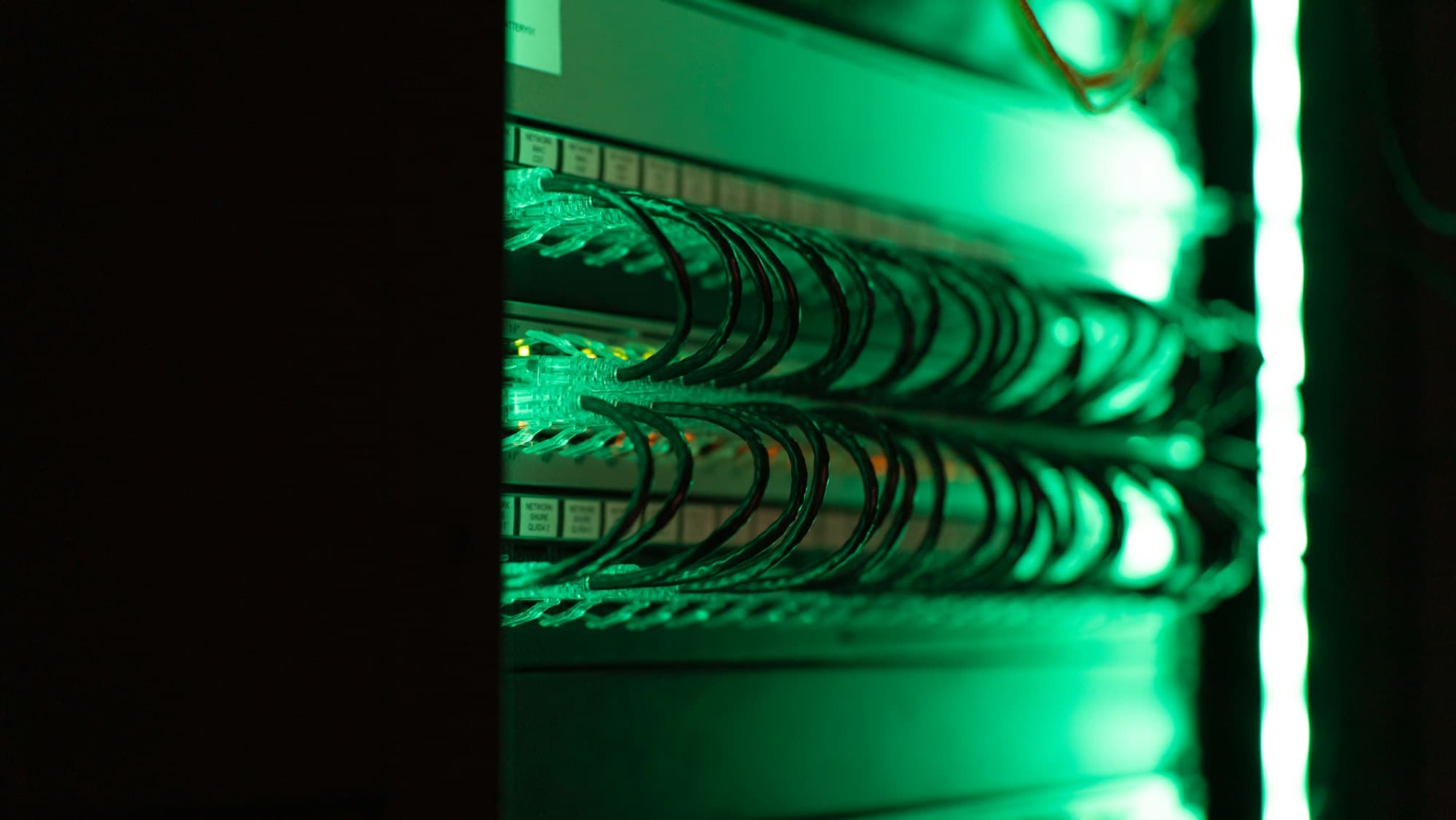 Server racks lit with green lights in a data center