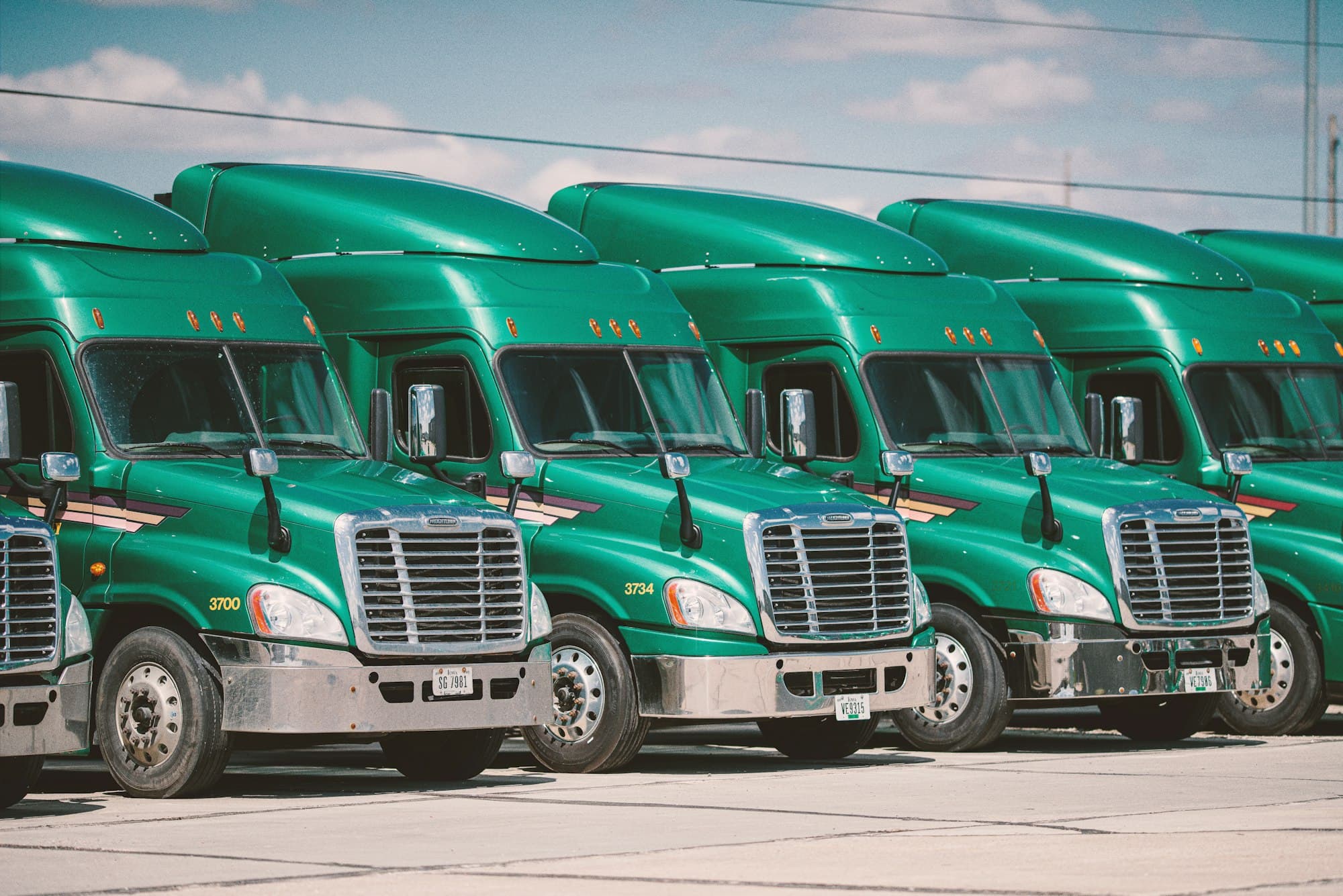 A row of green delivery trucks parked at a depot